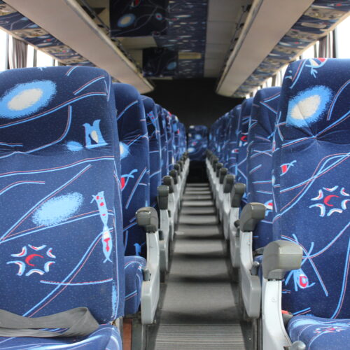 Spacious interior of our 71-seater bus available for bus hire in Johannesburg, featuring comfortable cloth seats, parcel shelves, and safety belts – perfect for school trips, events, and private group transport | TAG Passenger Services